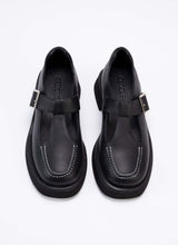 Lade das Bild in den Galerie-Viewer, Draufsicht eines Mary Jane Schuhs aus schwarzem Echtleder mit weißer Naht auf der Front. Gut zusehen ist der T-förmige Riemen mit Aussparung sowie die silberfarbene Schnalle. Gefüttert ist das Modell mit schwarzem Leder.