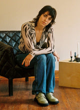 Lade das Bild in den Galerie-Viewer, Frau in Bluse mit Zebramuster und Jeans sitzt in einem Ledersessel. Sie trägt hellgrüne Monk-Schuhe aus Leder von Cedoublé.