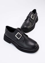 Load image into Gallery viewer, Ein Paar luxuriöse Halbschuhe aus hochwertigem, schwarzem Leder mit Lederriemen über dem Spann und silberfarbener, eckiger Schnalle. Auch die Sohle und das Futter sind passend schwarz. Die Schuhe sind vom Hersteller Cedoublé und werden unter fairen Bedingungen in Europa produziert.