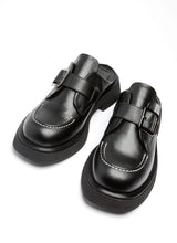 Lade das Bild in den Galerie-Viewer, Ein Paar Clogs aus Leder. Die Schuhe sind typisch für einen Clog vorne geschlossen und hinten offen. Es handelt sich um schwarzes, hochwertiges Echtleder, die Front wird geziert von einer weißen Kontrastnaht. Über den Spann verläuft eine silberfarbene Monk-Schnalle.