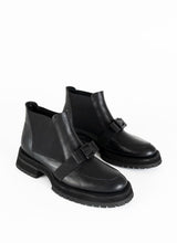 Lade das Bild in den Galerie-Viewer, Ein Paar schwarze Chelseaboots aus Leder mit weitflächigem Elastikeinsatz und dekorativer Schnalle in Schleifenoptik. Dieses Schleifendetail schmiegt sich über den Spann.