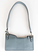 Lade das Bild in den Galerie-Viewer, Rückansicht einer Crossbody Tasche aus grauem Leder. Diese Tasche ist von der Marke Cedoublé. Sie verfügt über drei Taschenabteile, welche entweder mit Druckknopf oder Reißverschluss geschlossen werden können. Der Taschenhenkel kann mittels Karabinerhaken ausgetauscht oder abgenommen werden. Das Leder ist ein hochwertiges Kalbsleder, das Futter ist ein Lammleder. Der Taschenkörper ist leicht gefüttert. Insgesamt eine sehr praktische Tasche für viele Anlässe.