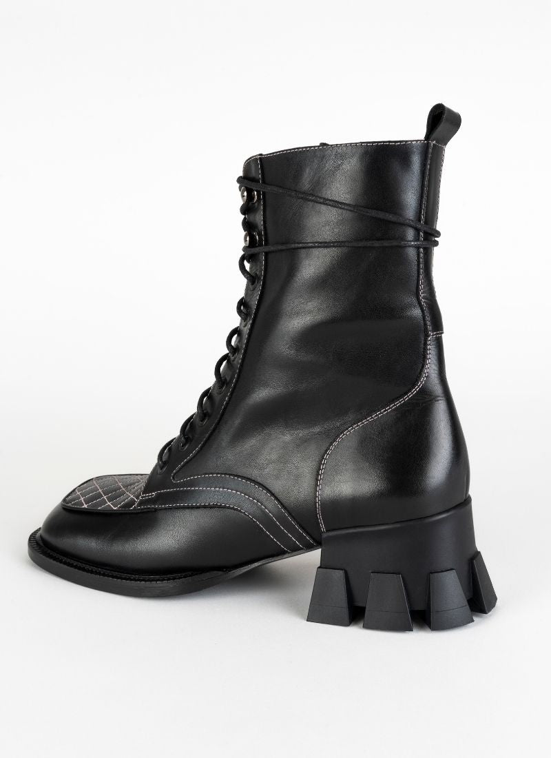 Schwarze Schnürboots mit Karreefront und Nähten in pink. Im Fokus steht der markante, skulpturale Absatz mit breiter Auftrittsfläche und Profil. Der Absatz ist ca. 5,5 cm hoch.