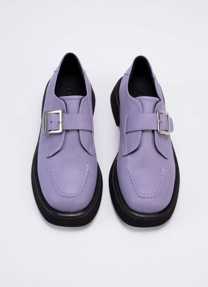 Draufsicht eines Unisex Schuhs, der in vielen Größen für Männer und Frauen erhältlich ist. Gut zu erkennen ist das lavendelfarbene Echtleder sowie das schwarze Lederfutter. Das Modell verfügt über einen Riegel über dem Spann. Dieser Riemen besitzt eine silberfarbene Schnalle.